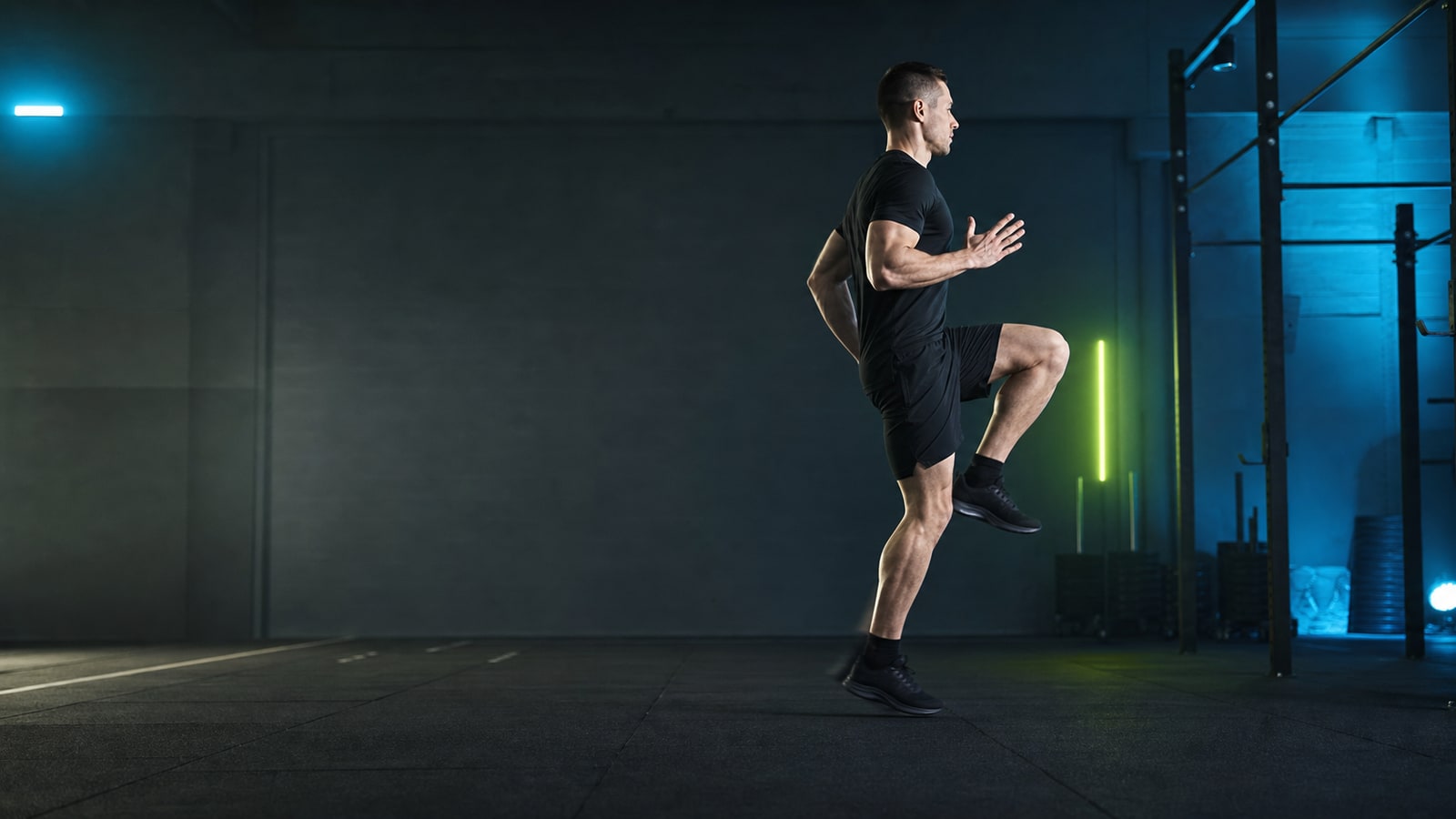 Athlete performing a controlled running drill in a dark indoor training hall