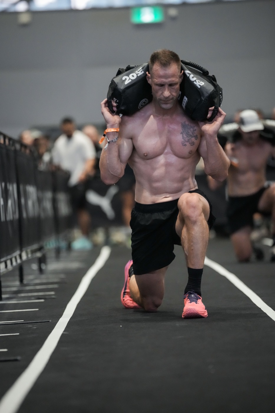 Tyson Schubert carrying a 20 kg sandbag during walking lunges at HYROX Sydney at age 45